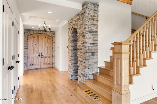 entrance foyer featuring an inviting chandelier, hardwood / wood-style flooring, stairs, and crown molding