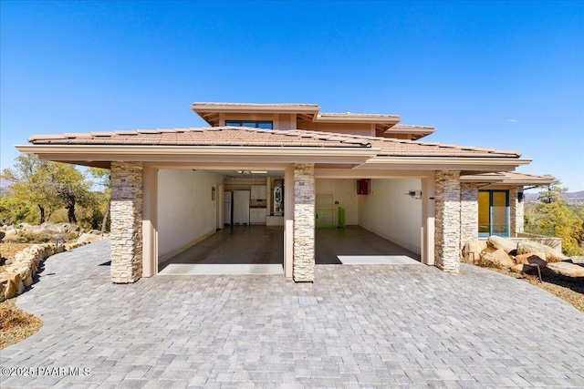 prairie-style house featuring decorative driveway, roof mounted solar panels, and stucco siding