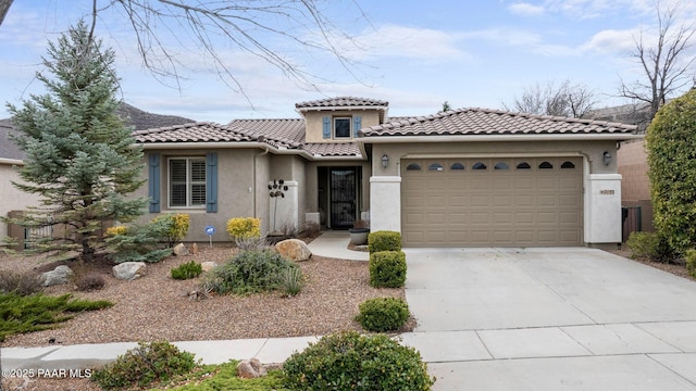 mediterranean / spanish-style home with a tile roof, stucco siding, concrete driveway, and a garage