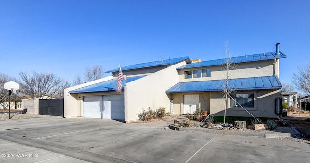 view of front of home with stucco siding, concrete driveway, an attached garage, a standing seam roof, and metal roof