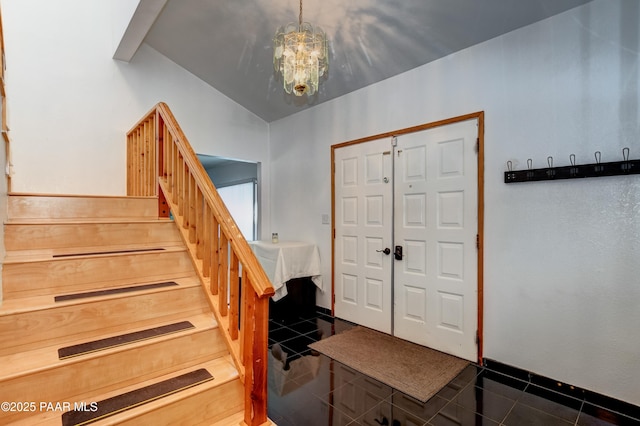 entrance foyer featuring lofted ceiling, dark tile patterned floors, baseboards, stairway, and an inviting chandelier