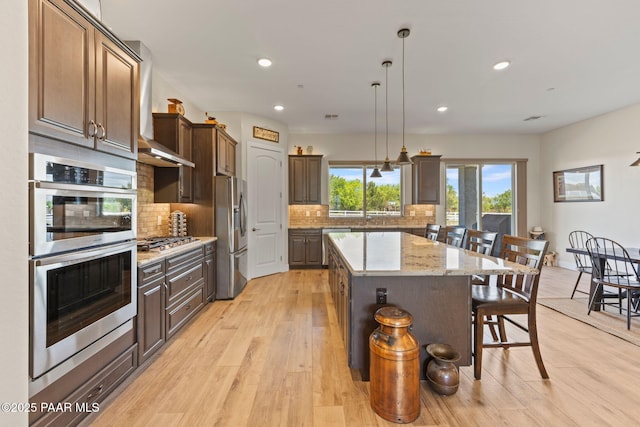 1450 Henry Dr, Chino Valley, AZ 86323 - kitchen featuring appliances with stainless steel finishes, a kitchen island, a breakfast bar, backsplash, and light wood-style flooring