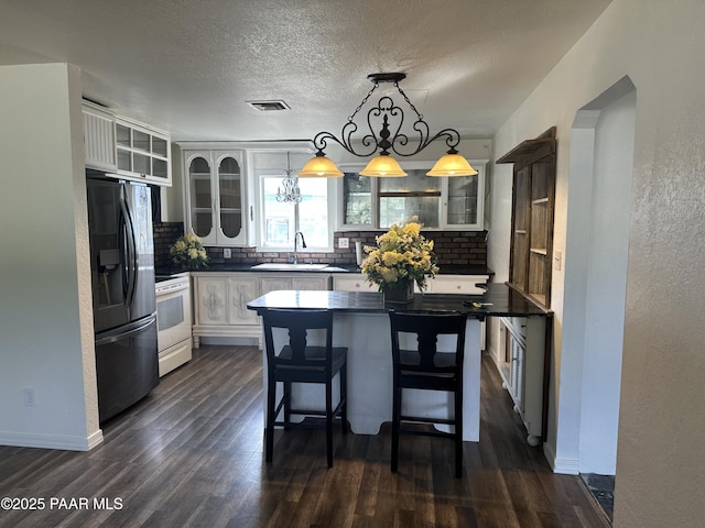 2532 Huron St, Dewey-Humboldt, AZ 86329 - kitchen featuring refrigerator with ice dispenser, white range with electric cooktop, tasteful backsplash, dark countertops, and dark wood finished floors