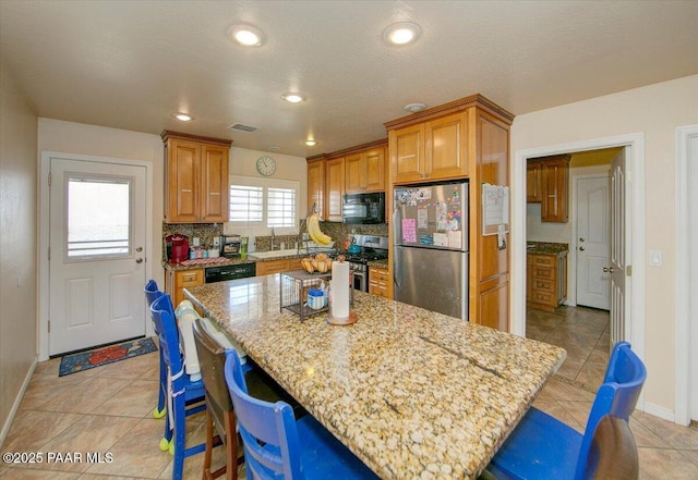 2770 Azurite St, Dewey-Humboldt, AZ 86327 - kitchen featuring black appliances, a kitchen breakfast bar, light stone counters, decorative backsplash, and a center island