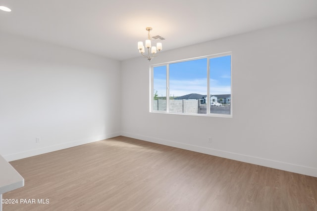 unfurnished room featuring a notable chandelier and wood-type flooring