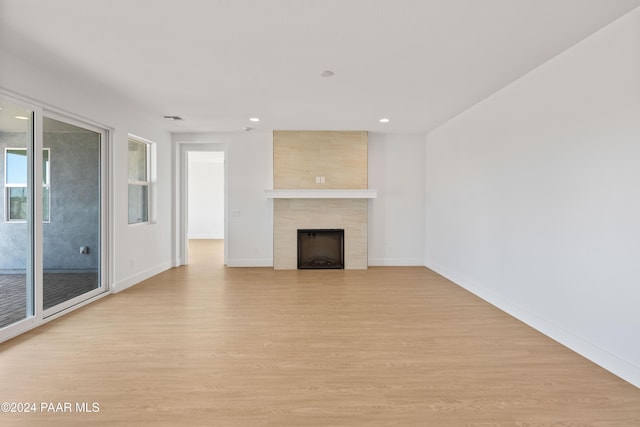 unfurnished living room featuring a tile fireplace and light hardwood / wood-style floors