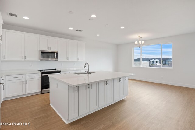 kitchen featuring white cabinets, sink, stainless steel appliances, and an island with sink