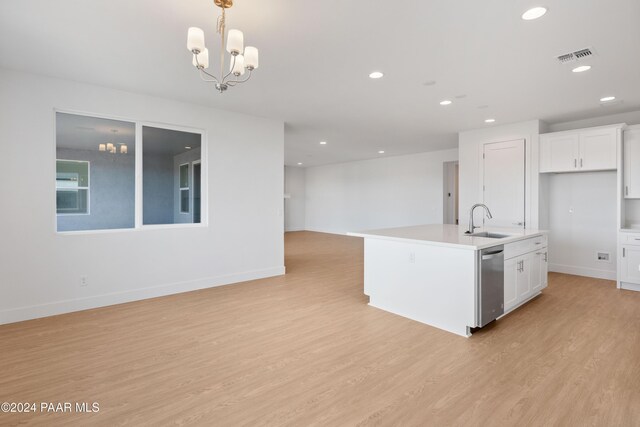 kitchen featuring light wood-type flooring, sink, decorative light fixtures, white cabinets, and an island with sink