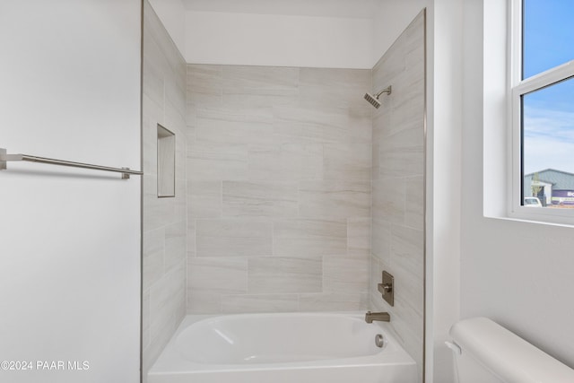 bathroom with tiled shower / bath combo and toilet