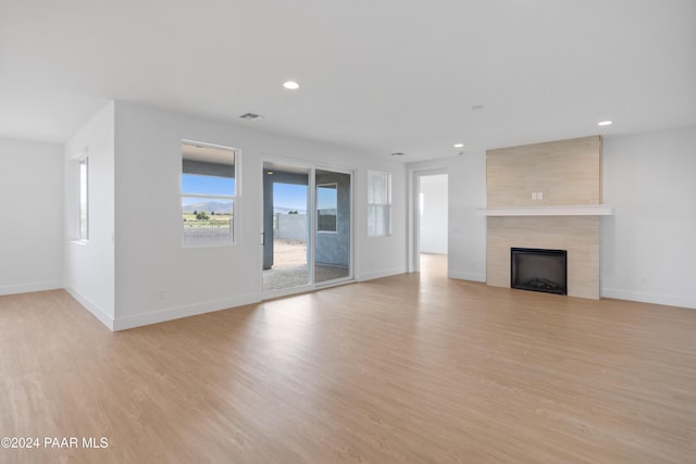 unfurnished living room with a tile fireplace and light hardwood / wood-style flooring