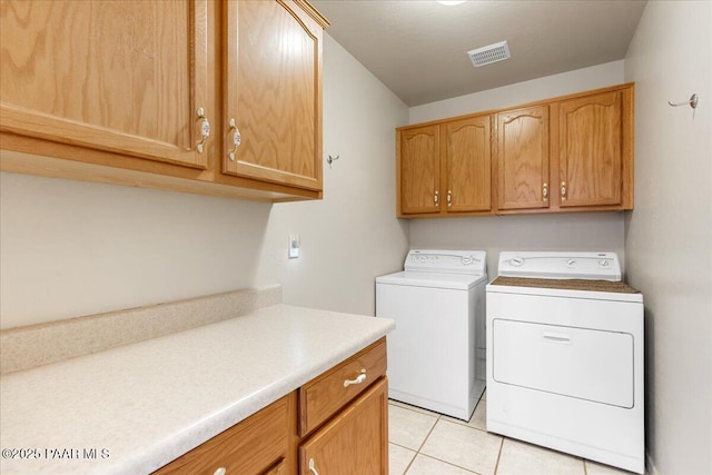 clothes washing area featuring washer and dryer, cabinets, and light tile patterned flooring
