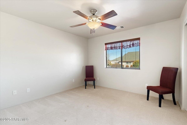 living area featuring light carpet and ceiling fan