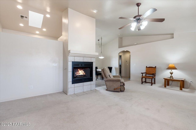 carpeted living room with high vaulted ceiling, a tile fireplace, and ceiling fan