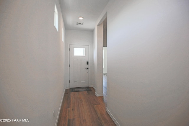 hall with baseboards, wood finished floors, and visible vents