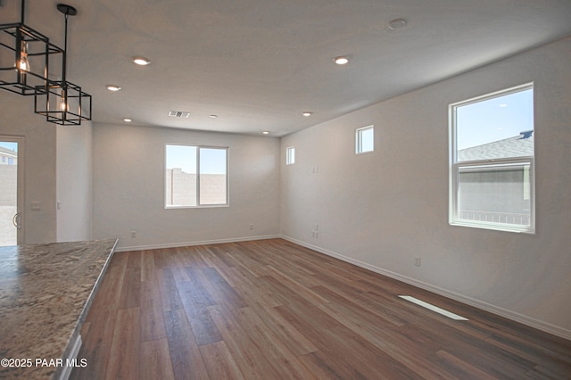unfurnished room with baseboards, wood finished floors, a healthy amount of sunlight, and visible vents