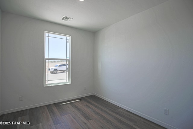 empty room with visible vents, baseboards, and dark wood-style floors