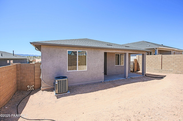 back of property featuring a patio area, cooling unit, a fenced backyard, a shingled roof, and stucco siding