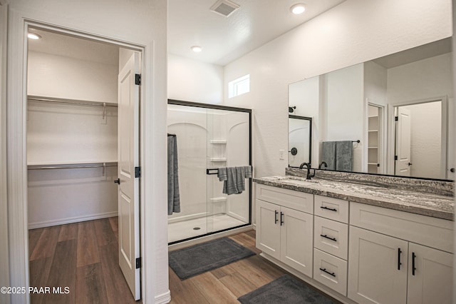 full bathroom featuring visible vents, a shower stall, wood finished floors, and vanity