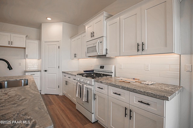 kitchen featuring recessed lighting, a sink, white cabinetry, and white appliances