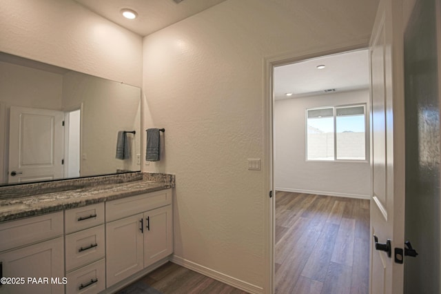bathroom featuring baseboards, a textured wall, vanity, and wood finished floors