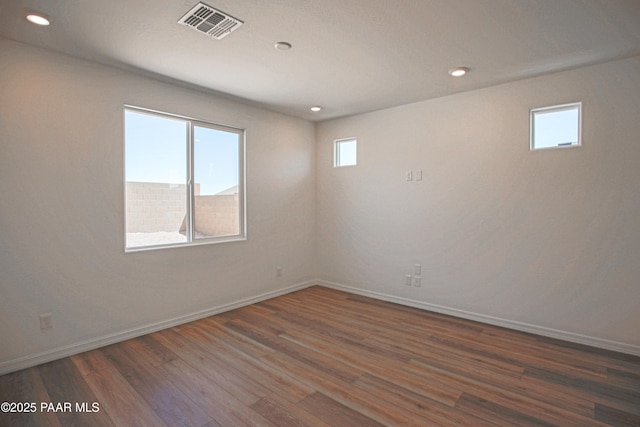 empty room featuring baseboards, recessed lighting, wood finished floors, and visible vents