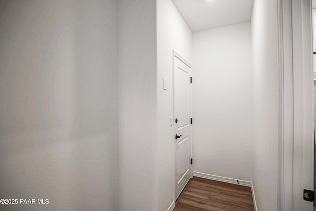 corridor featuring baseboards and dark wood-type flooring