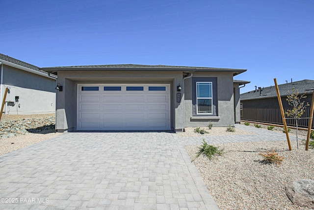 view of front of house featuring fence, stucco siding, an attached garage, and decorative driveway