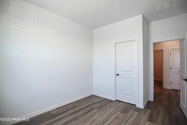 unfurnished bedroom featuring visible vents, dark wood-style flooring, and baseboards