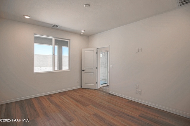 empty room with visible vents, dark wood finished floors, and baseboards