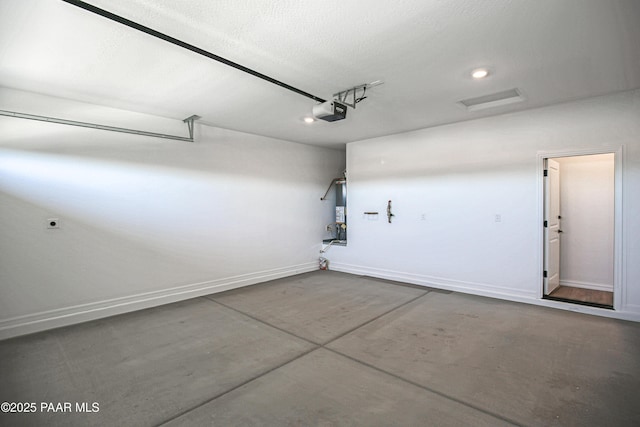garage featuring baseboards, a garage door opener, water heater, and recessed lighting