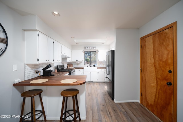17571 E Hummingbird Ln, Mayer, AZ 86333 - kitchen with stainless steel range with gas cooktop, high end fridge, decorative backsplash, under cabinet range hood, and a peninsula