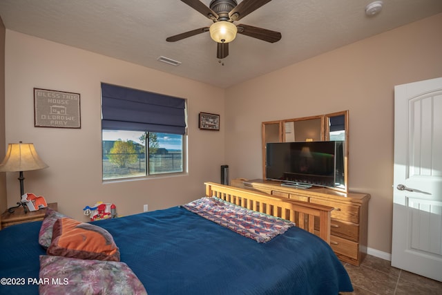 tiled bedroom featuring ceiling fan and a textured ceiling