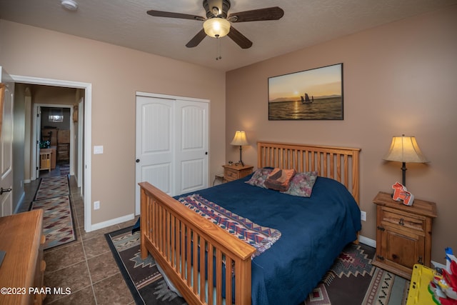 bedroom featuring a textured ceiling, dark tile patterned floors, a closet, and ceiling fan