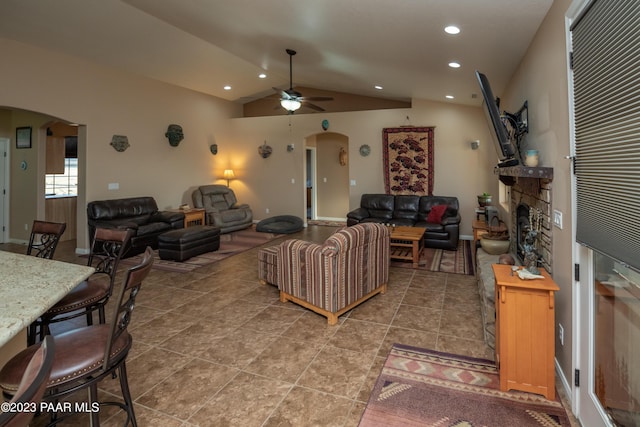 living room with ceiling fan, a fireplace, and vaulted ceiling