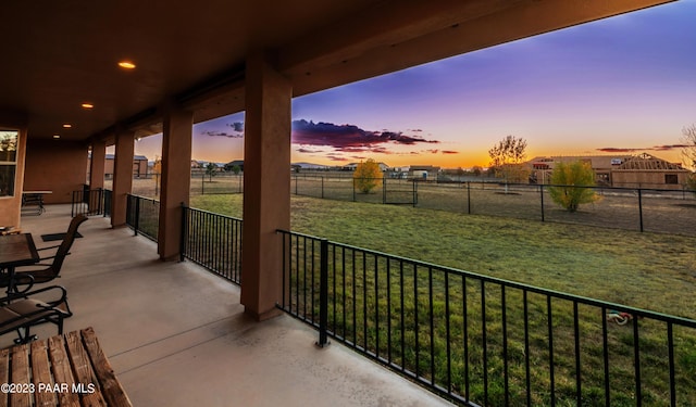 patio terrace at dusk featuring a yard