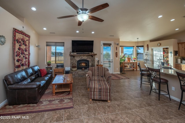 living room featuring vaulted ceiling, a stone fireplace, ceiling fan, and sink