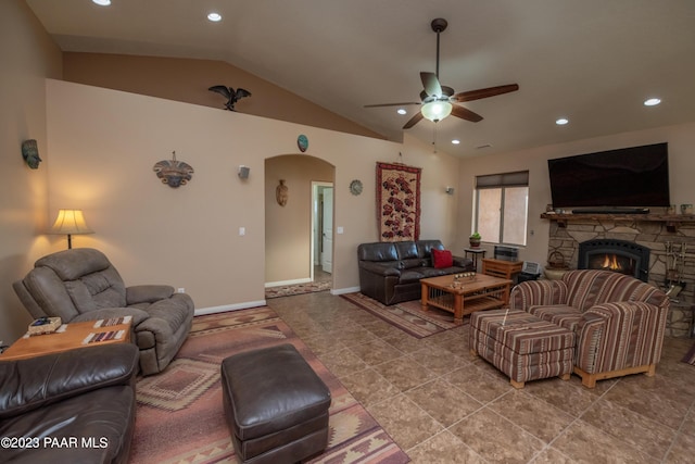 tiled living room with a stone fireplace, ceiling fan, and lofted ceiling