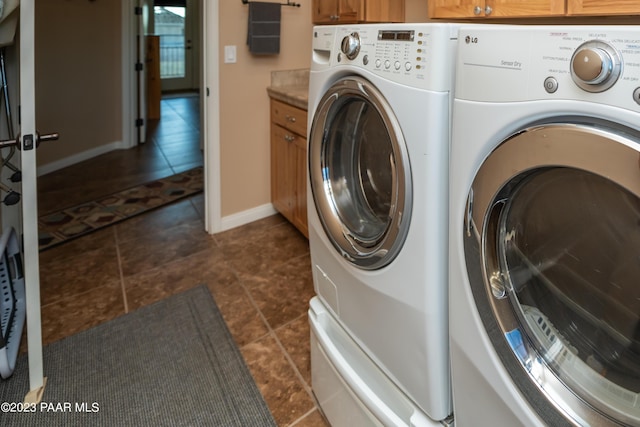 laundry room with washer and clothes dryer, cabinets, and dark tile patterned flooring