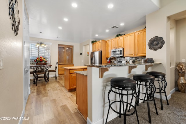 kitchen featuring pendant lighting, stone counters, stainless steel appliances, tasteful backsplash, and kitchen peninsula