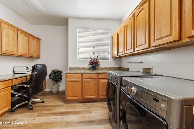 laundry room with cabinets, washer and dryer, and light wood-type flooring