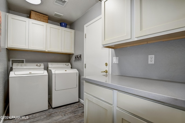 laundry area featuring washer and clothes dryer, cabinets, and wood-type flooring