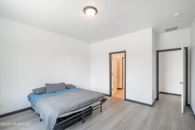 bedroom featuring ensuite bathroom and light hardwood / wood-style flooring