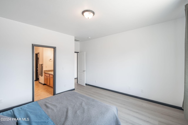 bedroom with light wood-type flooring and ensuite bath