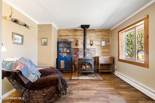 living room with a wood stove, ornamental molding, baseboard heating, and wood finished floors