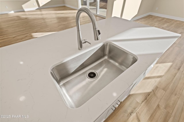 interior details featuring sink, light stone counters, and light hardwood / wood-style flooring