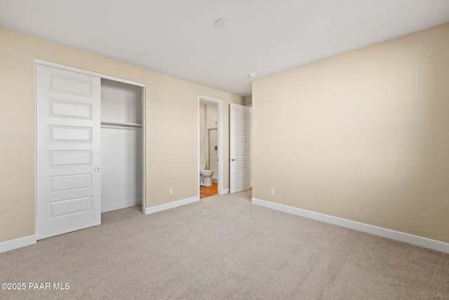 unfurnished bedroom featuring light colored carpet, ensuite bath, and a closet