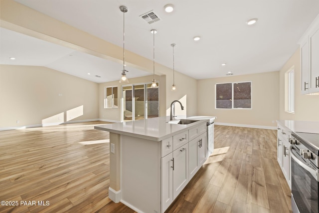 kitchen with white cabinetry, decorative light fixtures, a kitchen island with sink, and appliances with stainless steel finishes