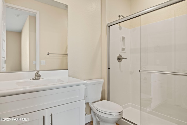 bathroom featuring vanity, toilet, and a shower with shower door