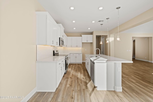 kitchen featuring sink, white cabinetry, hanging light fixtures, a center island with sink, and appliances with stainless steel finishes