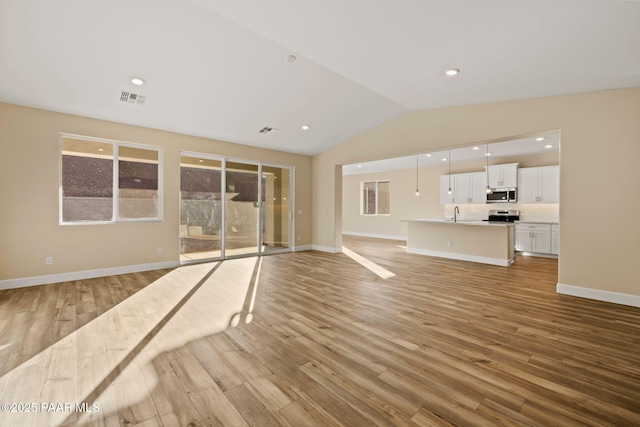 unfurnished living room featuring vaulted ceiling and light hardwood / wood-style flooring